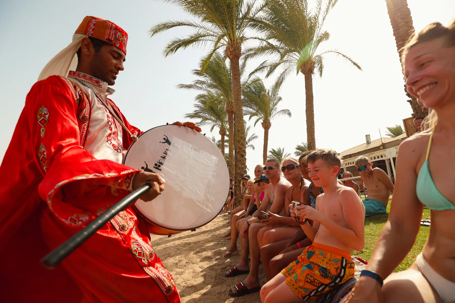 Traditional performer in costume playing a drum for guests on the beach at Caribbean World Resorts Hurghada