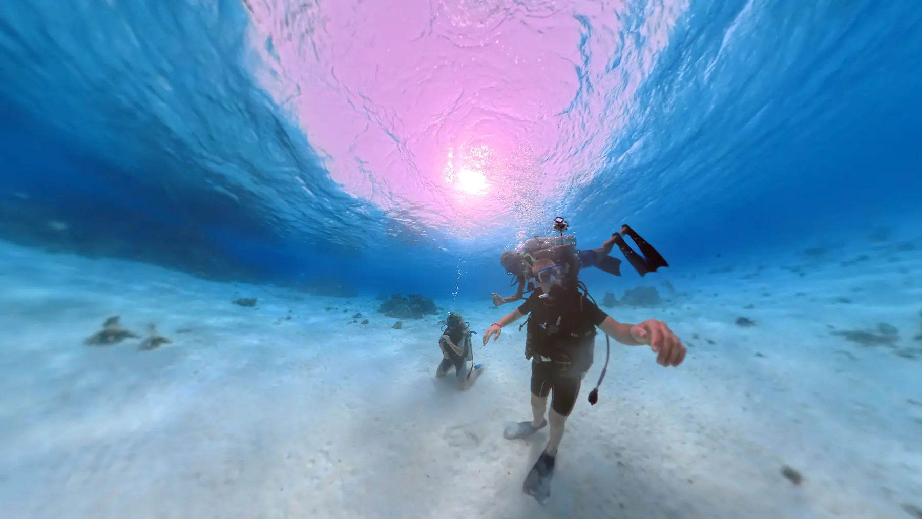 Three scuba divers approaching coral reef area in the Red Sea near Caribbean World Resorts Hurghada